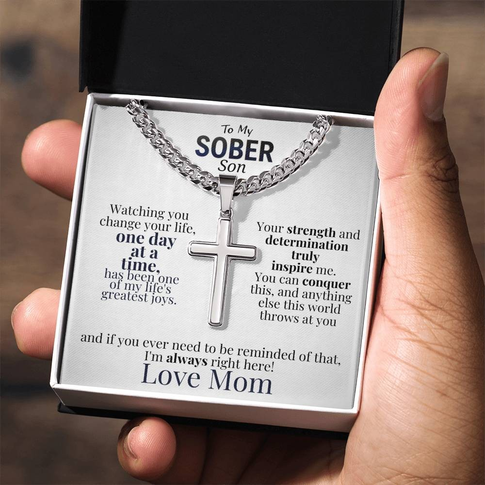 Cross necklace and message card in gift box with dark lid held in hand