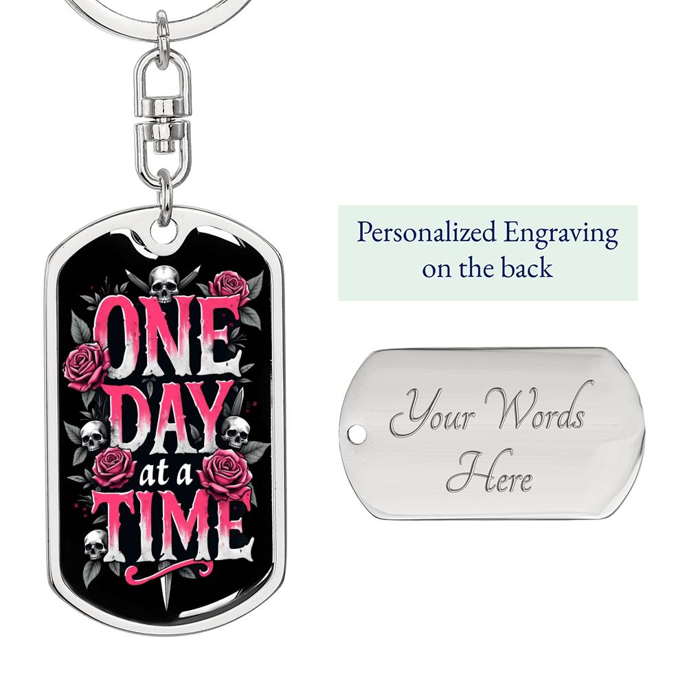Silver dog tag keychain with black graphic and pink text, plus engraved back panel