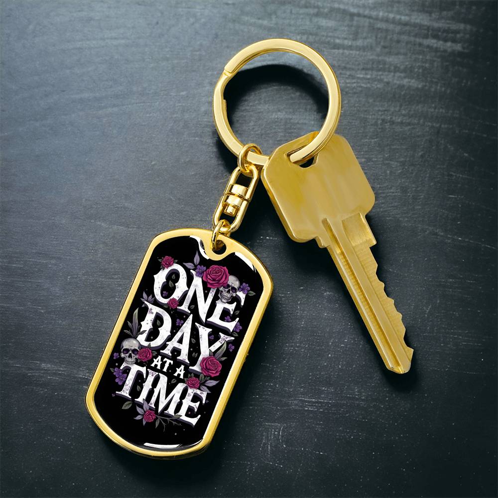 Gold dog tag keychain with “One Day At A Time” tag front and matching key