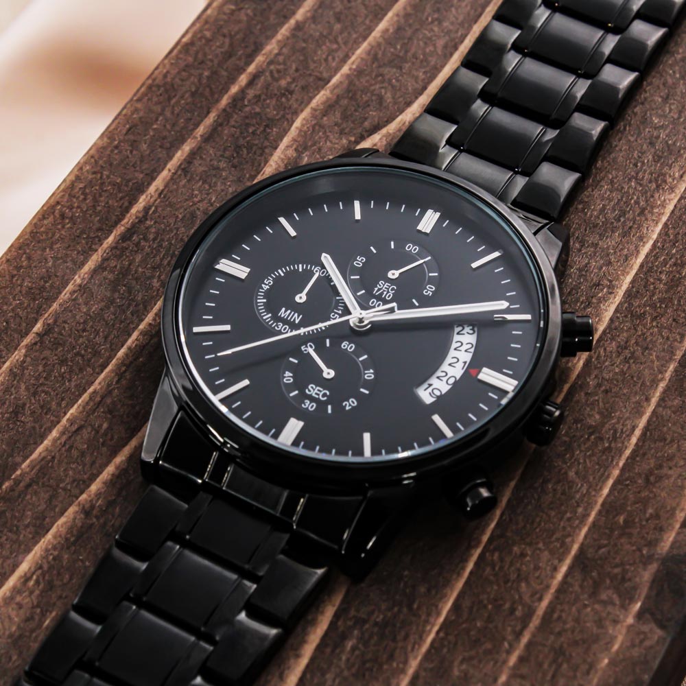 Men's black chronograph wrist watch on a wooden display with steel bracelet