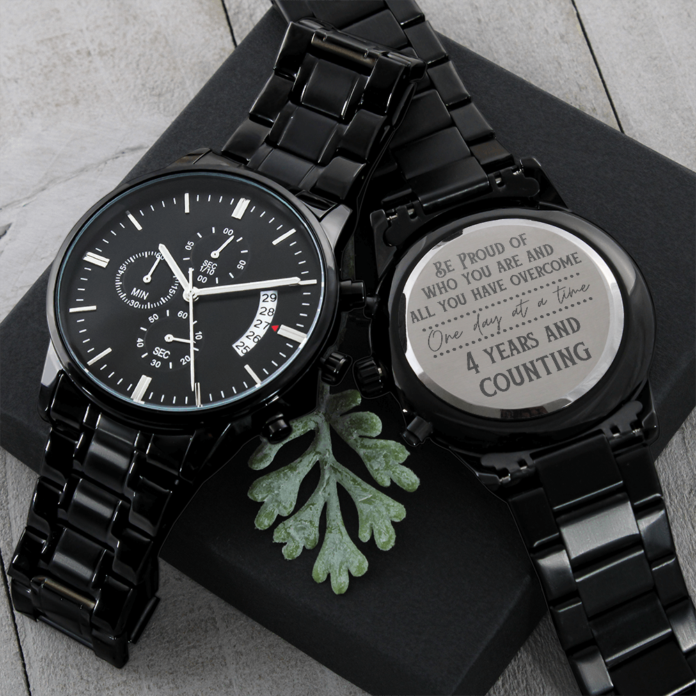 Black chronograph watch with linked metal bracelet and engraved case back