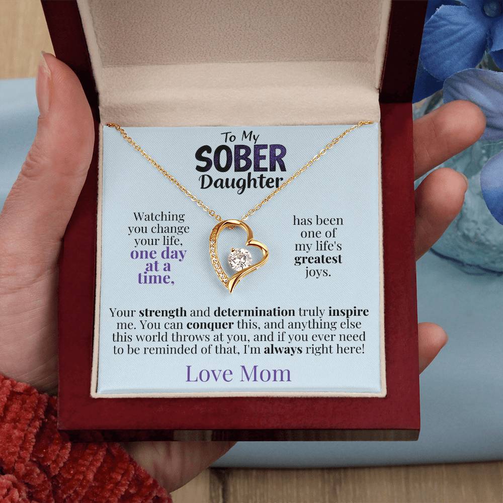 Gold heart pendant necklace in an open gift box, held in a hand