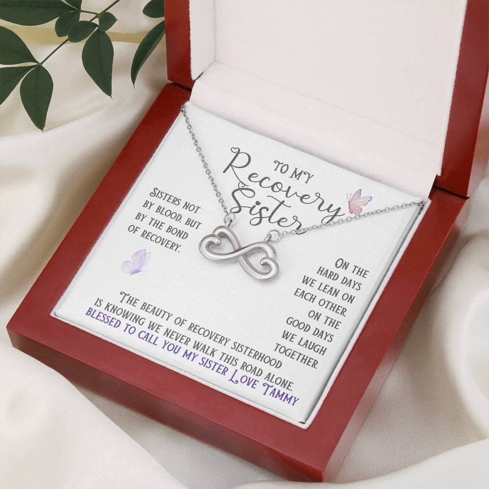 Silver infinity necklace with heart charm displayed in a red gift box