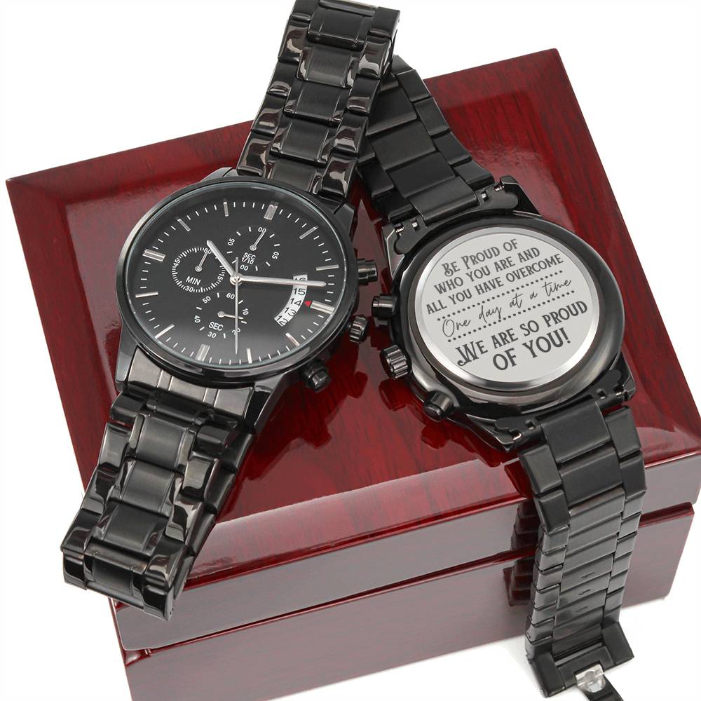 Black wristwatch with metal link band and silver engraved keepsake on gift box