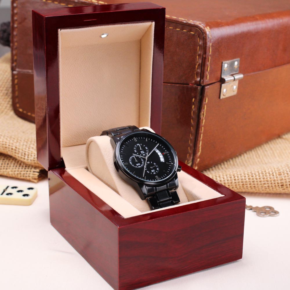 Black wristwatch on beige cushion inside brown leather-style gift box