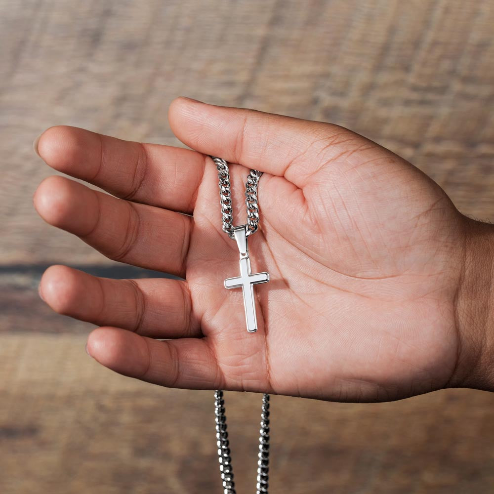 Silver-tone cross pendant necklace resting on palm with curb chain visible