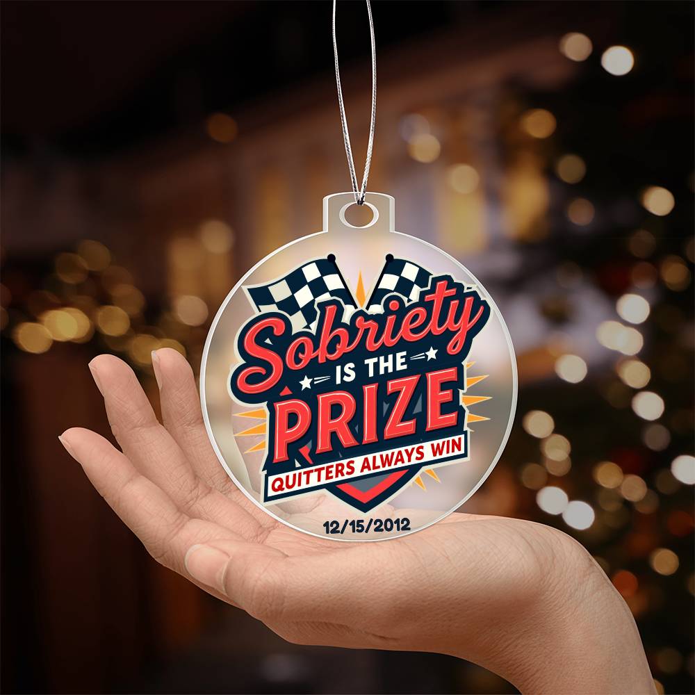 Round hanging ornament held in hand with “Sobriety Is The Prize” design and date