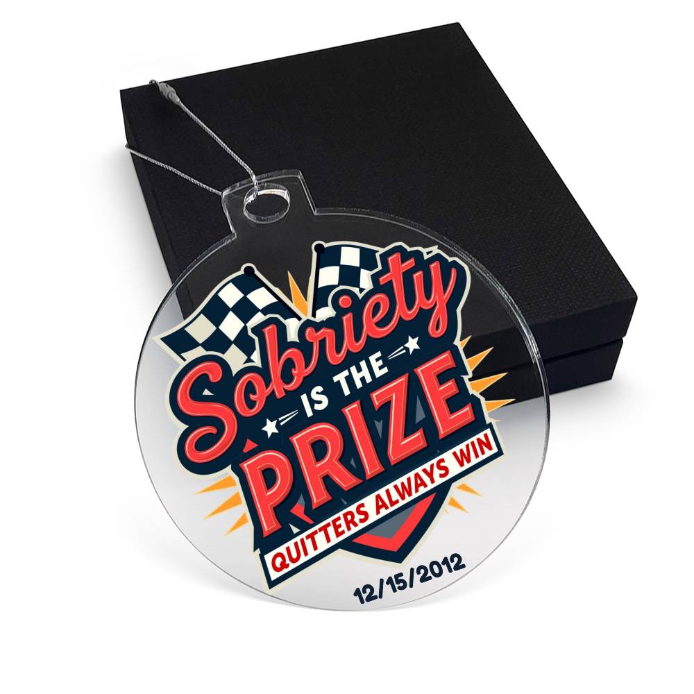 Round hanging ornament laid over black gift box with “Sobriety Is The Prize” design