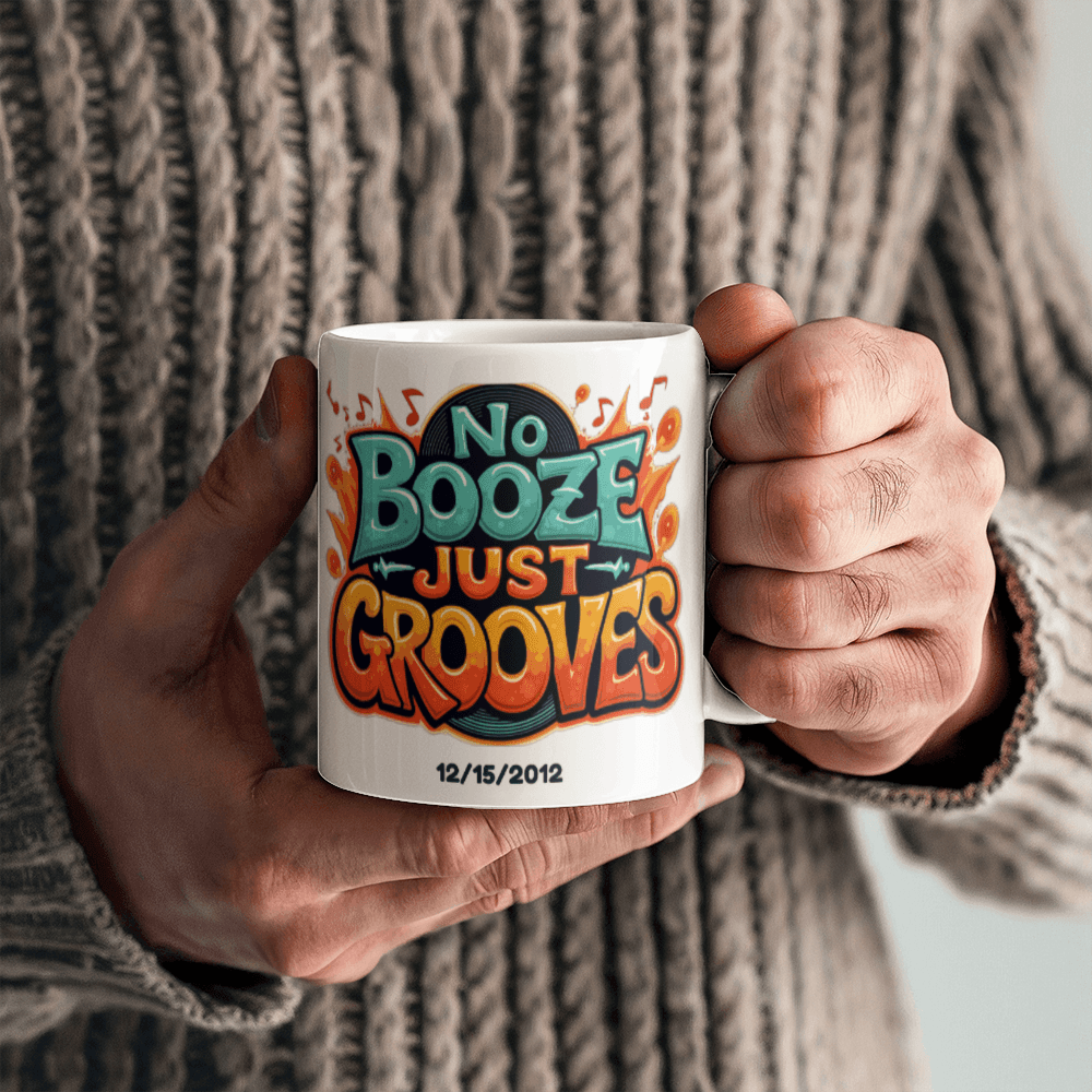 White ceramic mug gripped in hands with 'No Booze Just Grooves' print and date 12/15/2012