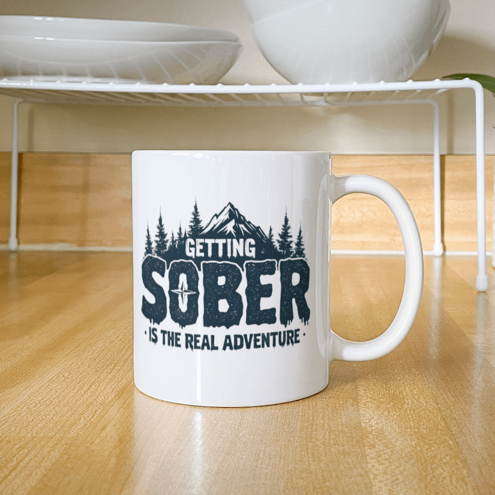 White ceramic mug with black 'GETTING SOBER' and 'is the real adventure' text