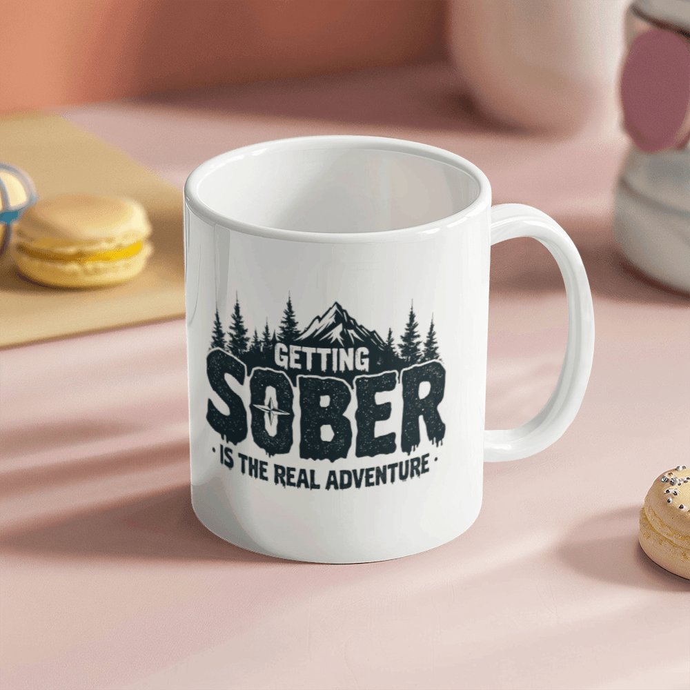 White ceramic mug showing black 'GETTING SOBER' and 'is the real adventure' lettering