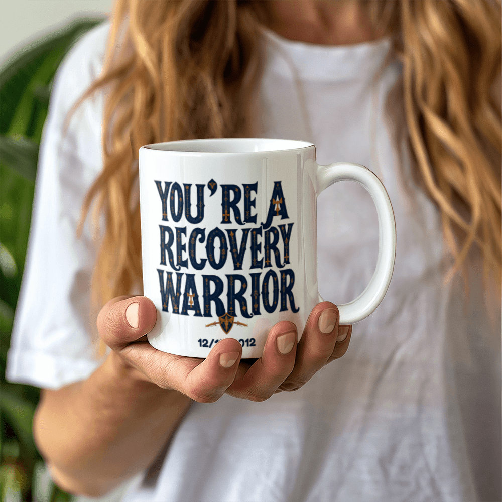 White coffee mug held in hands, featuring “You’re a Recovery Warrior” and date
