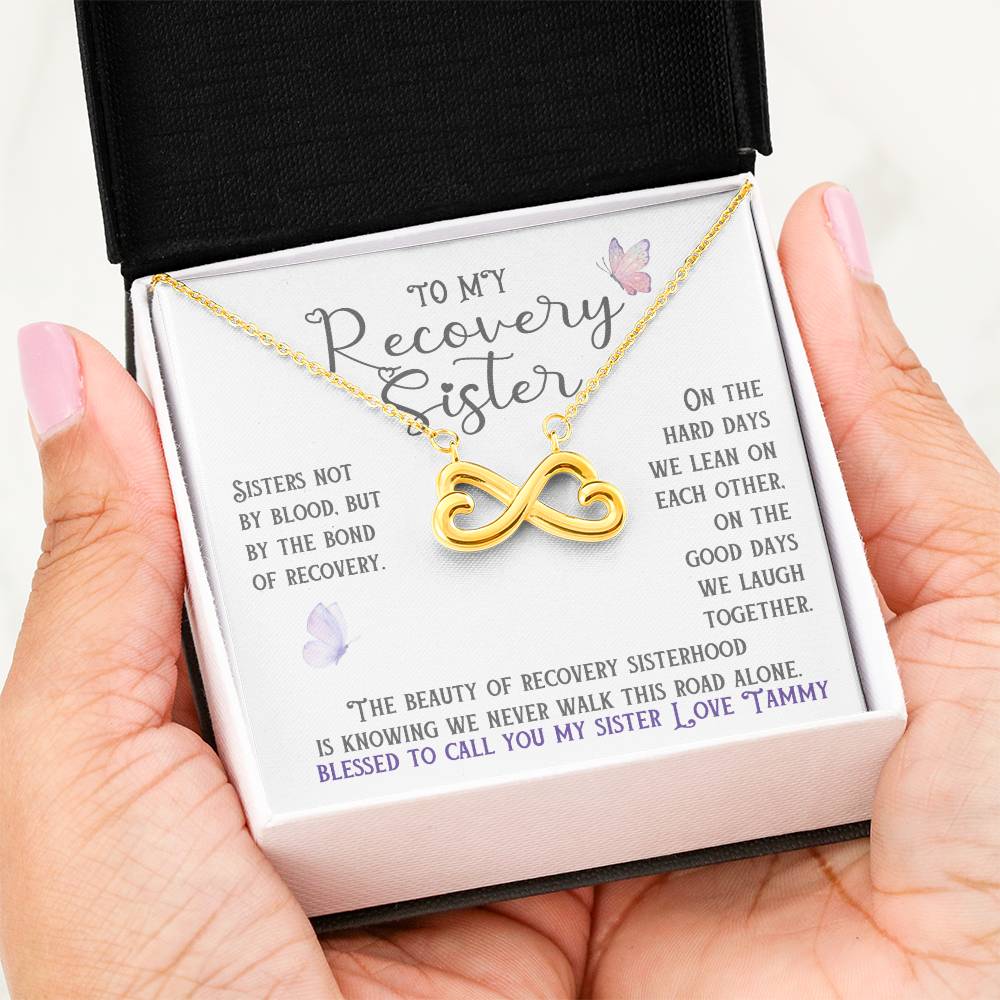 Gold infinity necklace with heart charm shown in a white gift box