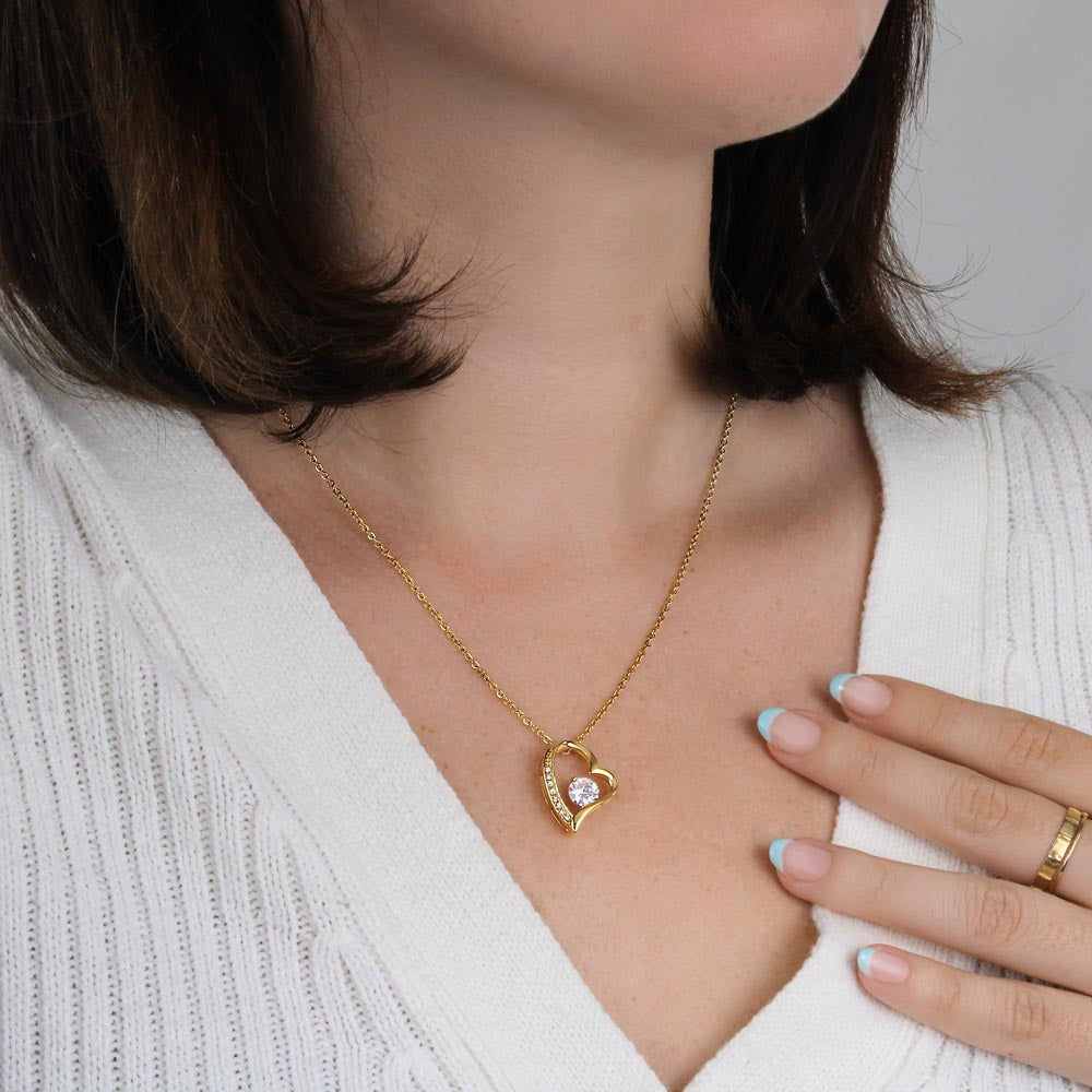 Gold heart pendant necklace worn on a model with a light V-neck sweater