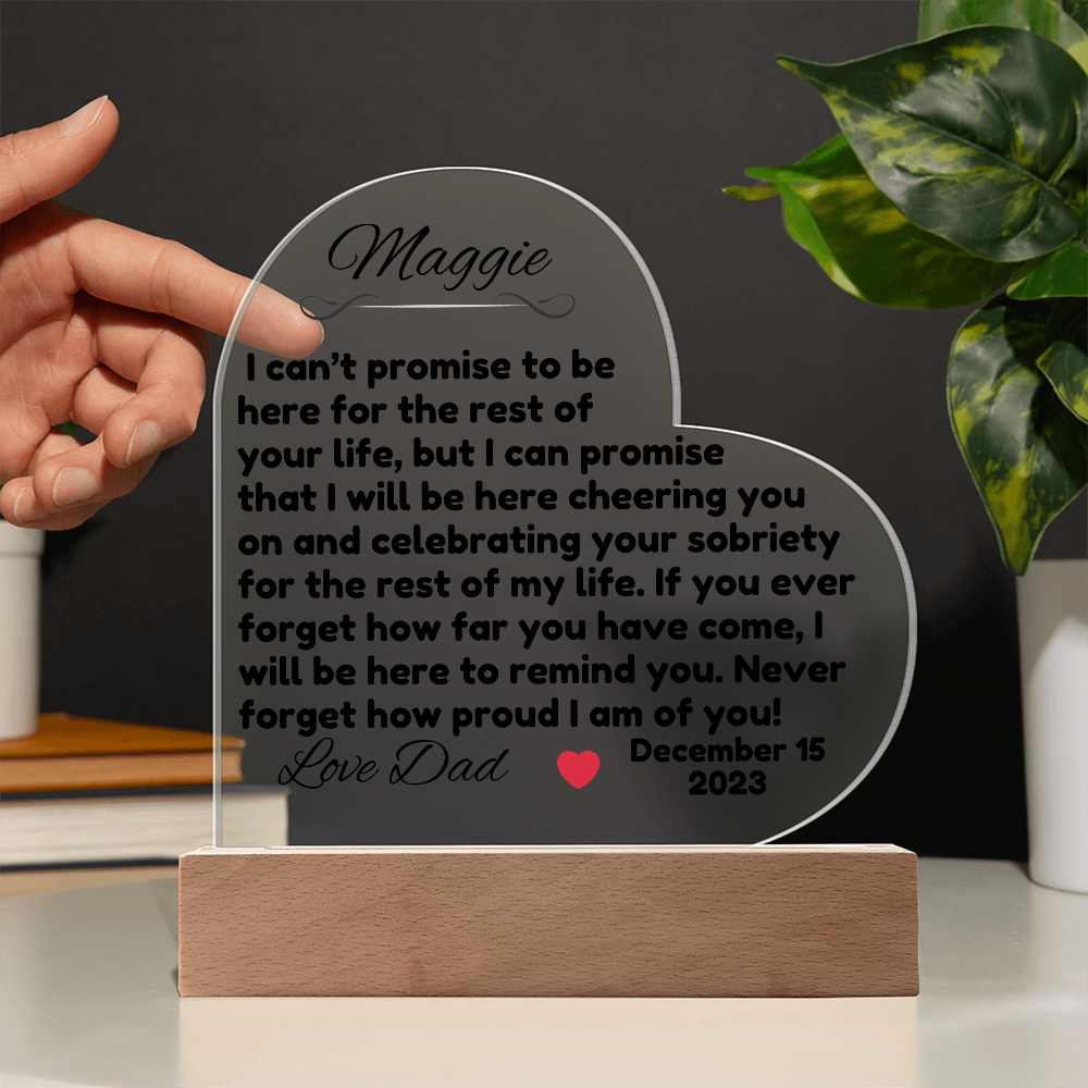 Acrylic LED heart sign with Maggie message on wooden base, held up by hand