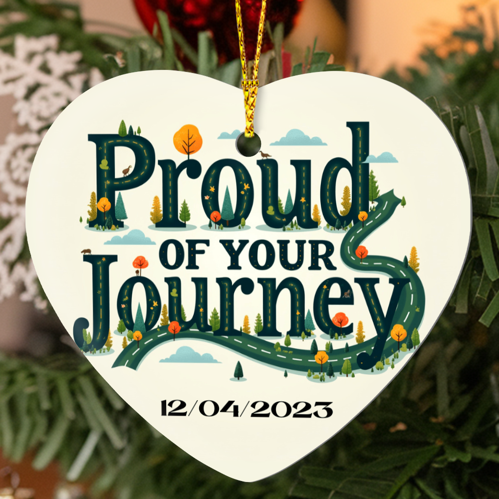 Heart ornament with “Proud of your Journey” and “12/04/2023”, hanging from gold cord.