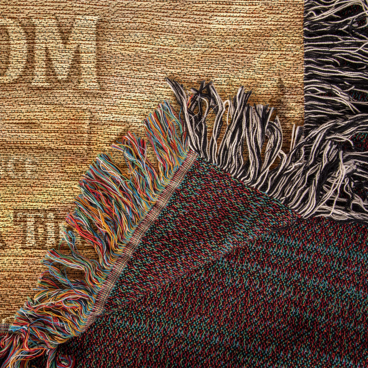 Beige woven blanket corner with multicolor threads and dark fringe trim