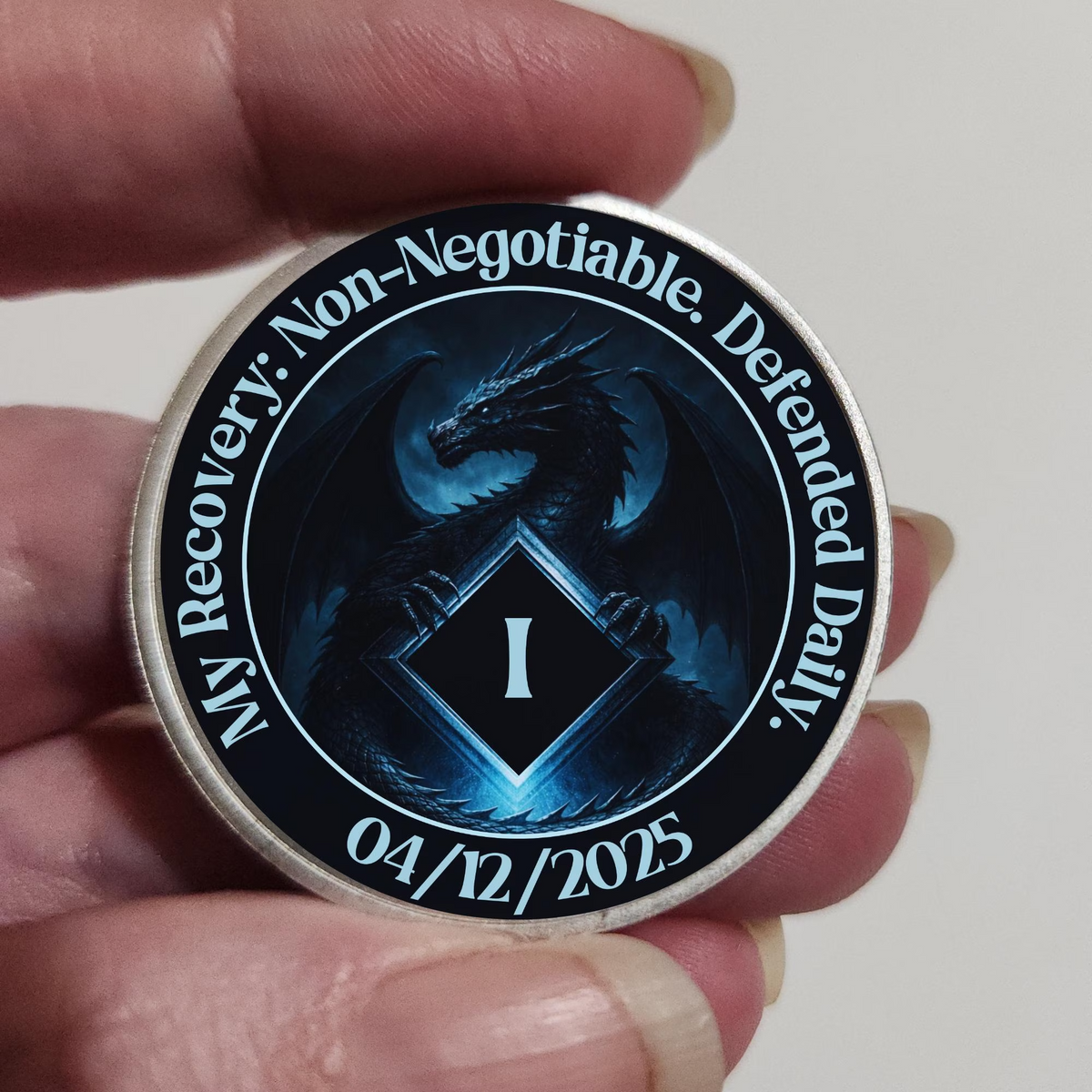 Recovery coin held in a hand with dark blue dragon emblem, “Non-Negotiable” and 04/12/2025.