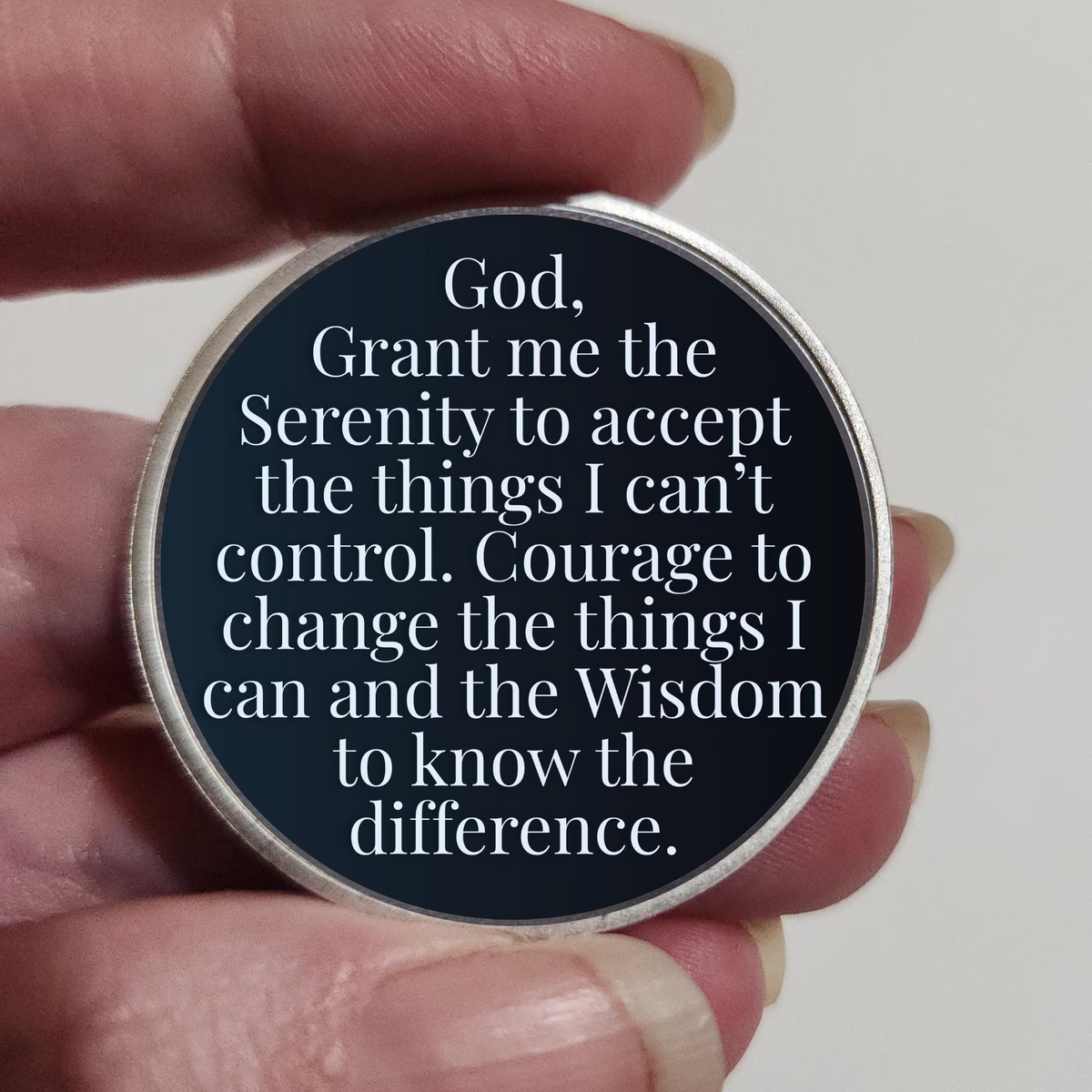 Round recovery coin held in hand with prayer text on dark background