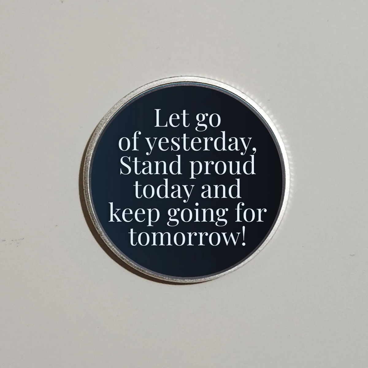 Round recovery coin with dark blue quote text and silver rim, “Let go of yesterday”.