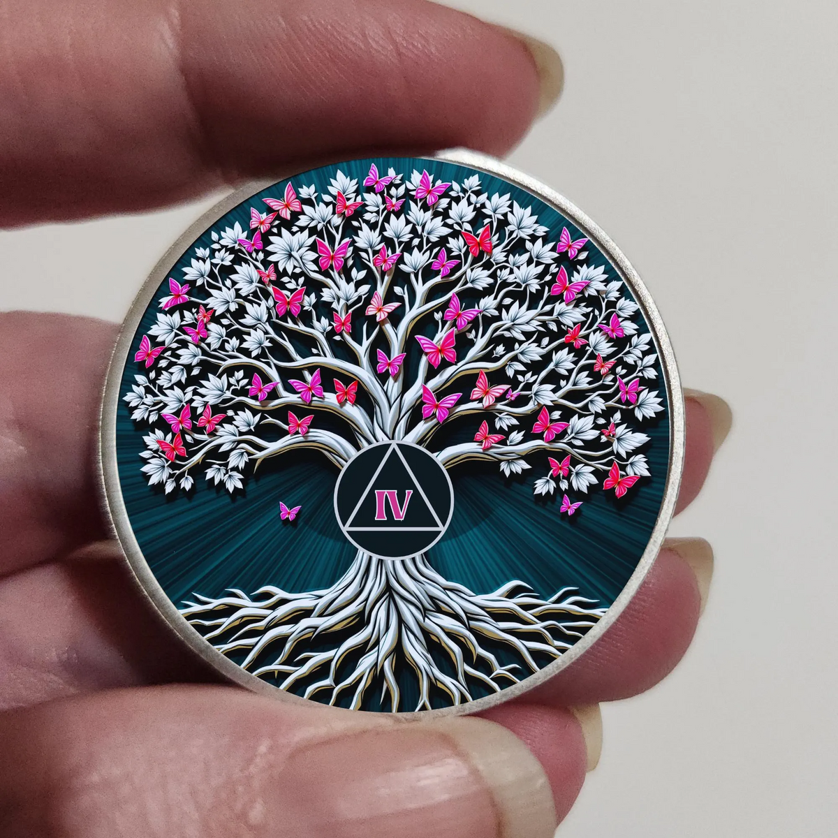 Hand holding silver-rim Tree of Life coin with butterfly tree artwork and Roman numeral IV